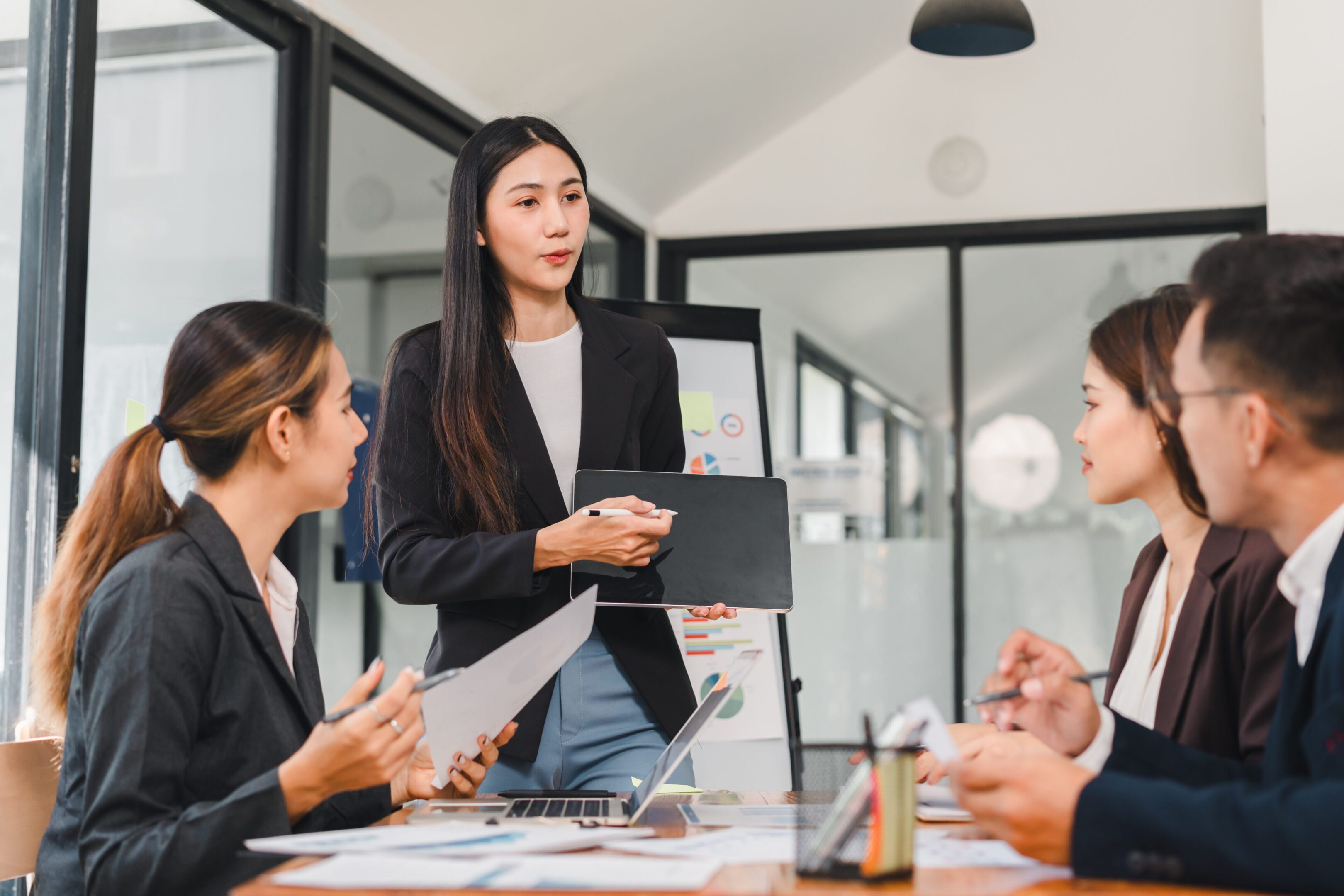 Professional woman presenting to group in modern office setting, showcasing teamwork and collaboration. atmosphere is focused and engaged, highlighting effective communication.